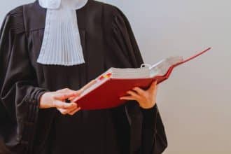 un-avocat-portant-une-toge-et-une-perruque-se-tient-devant-un-tribunal-pret-a-defendre-les-droits-des-personnes-defavorisees-dans-le-systeme-judiciaire-francais