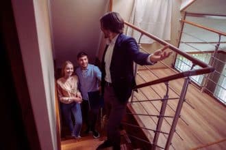Une agente immobilière discutant avec un client potentiel devant une maison, illustrant l'approche révolutionnaire pour booster votre réussite en prospection immobilière.