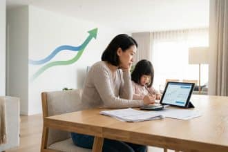 Woman and child at a table with financial documents, calculator, and tablet displaying a graph. Merging arrows symbolize financial growth.