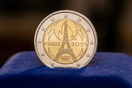 Photorealistic close-up of a polished Paris 2024 Olympic 2 euro coin featuring the Eiffel Tower and Olympic rings on dark blue velvet.