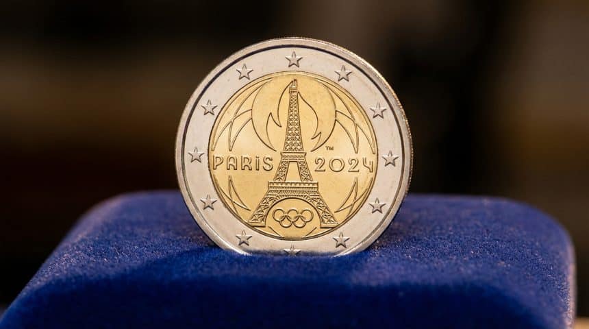 Photorealistic close-up of a polished Paris 2024 Olympic 2 euro coin featuring the Eiffel Tower and Olympic rings on dark blue velvet.