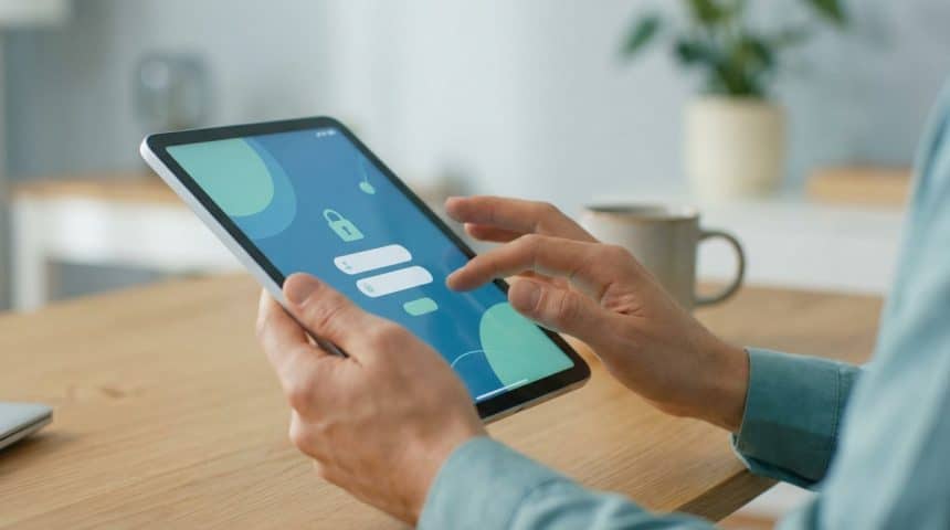Hands interact with a tablet displaying a secure login screen with a lock icon and input fields, in a soft-lit home setting.