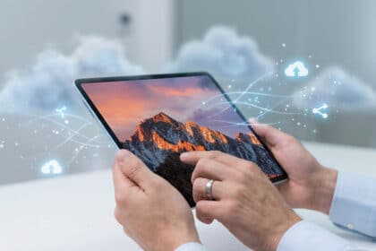 Mains tenant une tablette affichant une montagne, avec des icônes de nuage et de partage symbolisant l'hébergement et le transfert de données.