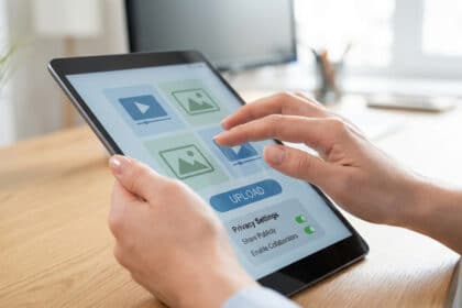 Mains utilisant une tablette affichant une interface d'upload de contenu avec des options de vidéo, image et paramètres de confidentialité.