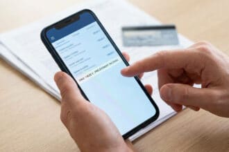 Main d'une personne touchant un écran de smartphone affichant un prélèvement inconnu de 108€ dans une app bancaire.