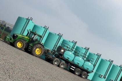 Tracteur vert devant réservoirs industriels turquoise
