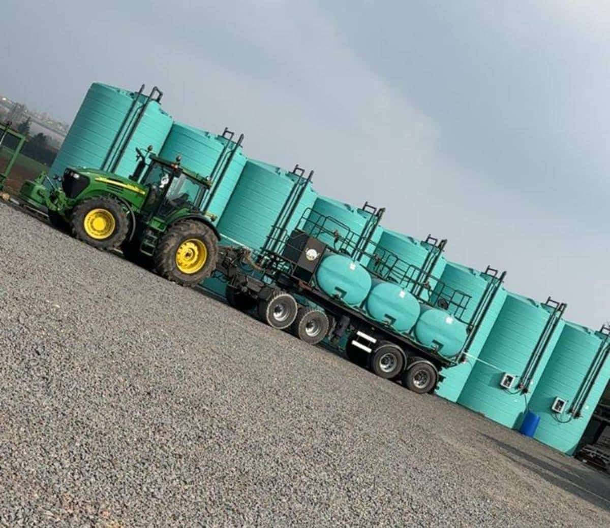 Tracteur vert devant réservoirs industriels turquoise